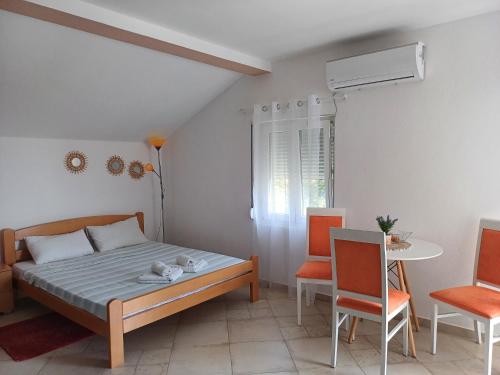 1 dormitorio con 1 cama, mesa y sillas en Apartments Papan, en Petrovac na Moru