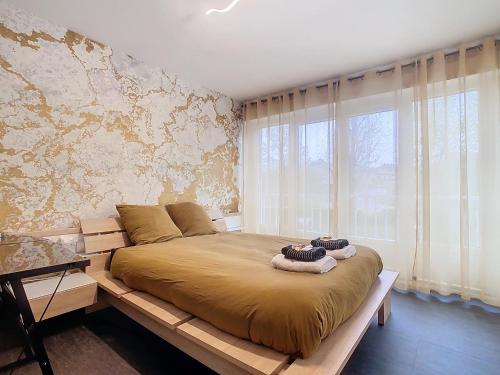 une chambre avec un grand lit et une grande fenêtre dans l'établissement L'Olivier de Lily, à Voiron