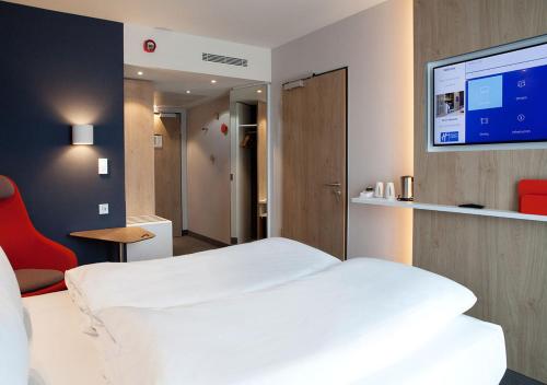 Schlafzimmer mit einem weißen Bett und einem Flachbild-TV in der Unterkunft Holiday Inn Express - Düsseldorf Airport in Düsseldorf