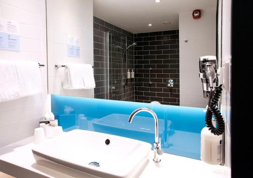 ein Bad mit einem Waschbecken und einem Spiegel in der Unterkunft Holiday Inn Express - Düsseldorf Airport in Düsseldorf