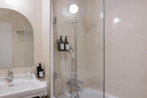 a white bathroom with a shower and a sink at ALFRED HOTELS Port-Vieux - Ex Georges VI in Biarritz