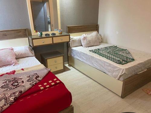 1 Schlafzimmer mit 2 Betten, einem Spiegel und einem Waschbecken in der Unterkunft Ilmontegalala in Ain Suchna
