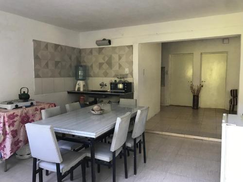a dining room with a table and white chairs at Casa en Río Grande in La Bajada