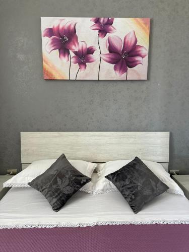 Una cama con dos pinturas de flores rosas. en Tenuta Pietro e Rosina, en Arnesano