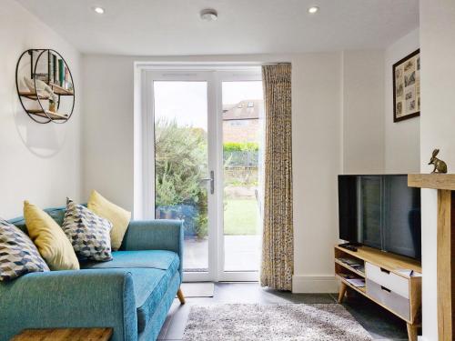 a living room with a blue couch and a tv at Four Priory Road, Chichester in Chichester