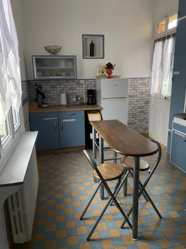 une cuisine avec des armoires bleues et une table et des chaises dans l'établissement maison de maitre, à Fleury-sur-Andelle