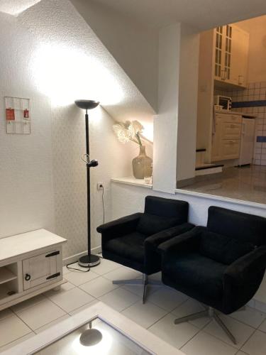 una sala de estar con 2 sillas negras y una lámpara. en 114 Village de Campagne - FONT MOURIER en Cogolin