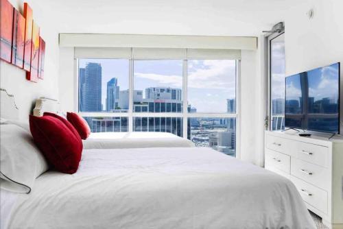 邁阿密的住宿－Beautiful apartment Miami, FL，白色卧室设有大窗户和一张带红色枕头的床