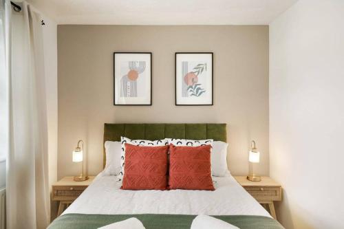 a bedroom with a bed with red pillows and two lamps at Cosy & Modern Property in London - Sleeps up to 6 in London
