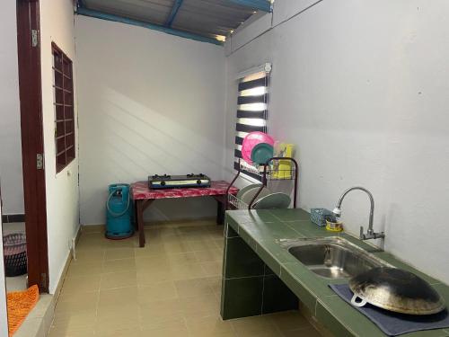 - une cuisine avec un évier et une table dans l'établissement Padang Besar Guesthouse Firdaus, à Padang Besar