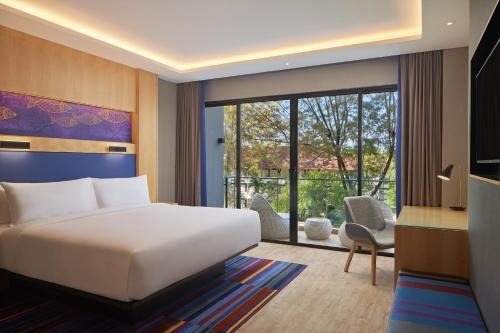 a hotel room with a bed and a large window at Aloft Langkawi Pantai Tengah in Pantai Cenang