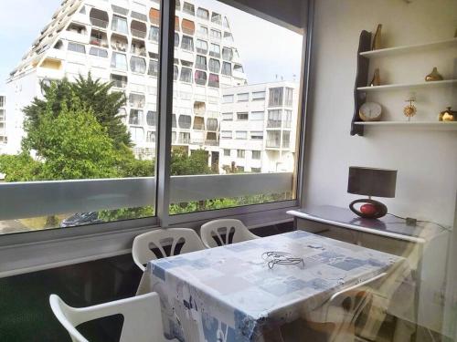 une table et des chaises dans une pièce avec une grande fenêtre dans l'établissement Nouveau! Studio centre-ville au calme, à La Grande Motte