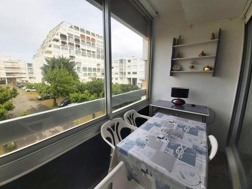 une table et des chaises dans une pièce avec une grande fenêtre dans l'établissement Nouveau! Studio centre-ville au calme, à La Grande Motte
