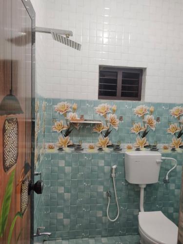 a bathroom with a shower and a toilet with flowers on the wall at Venu's Homestay in Varkala
