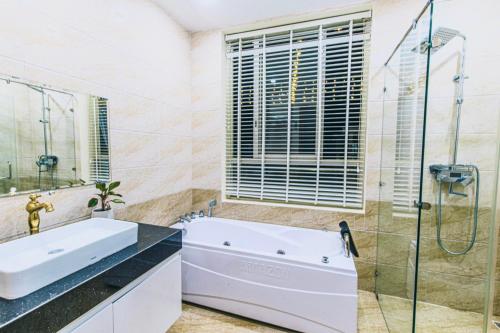 W łazience znajduje się wanna, umywalka i prysznic. w obiekcie Villa FLC Sầm Sơn Sao Biển SB106 w mieście Thanh Hóa