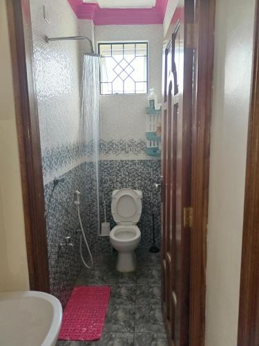 a bathroom with a toilet and a shower and a sink at Royals apartment in Mombasa