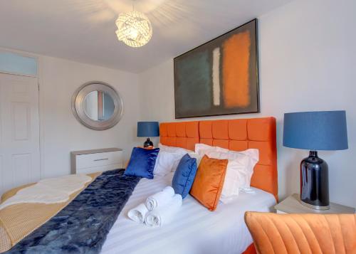Voguish 3BR Home in Huyton في ليفربول: غرفة نوم مع سرير مع اللوح الأمامي من البرتقال