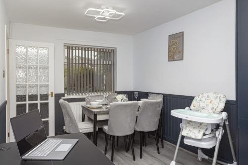 a dining room with a table and chairs and a laptop at Urban Gem in Longbridge