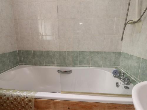 een badkamer met een wit bad en een wastafel bij Pendleside in Chatburn