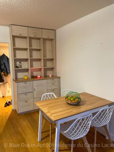 - une cuisine avec une table, des chaises et un bol de fruits dans l'établissement Appartement Blue Ocean, à Lacanau