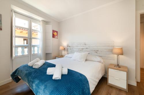 a bedroom with a white bed with towels on it at Carla,centro Llanes a 350m playa in Llanes