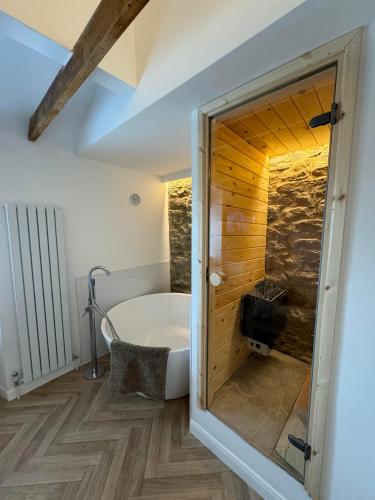 a bathroom with a tub and a wooden wall at Durham Dales Luxury Cottage in Stanhope