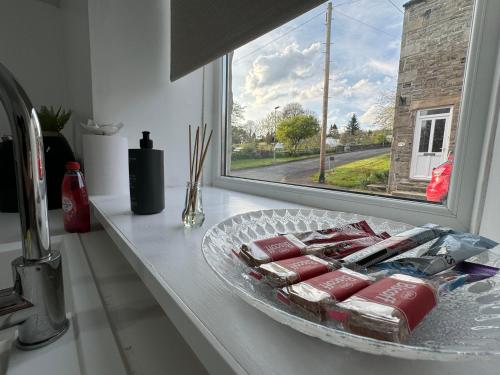 einen Teller Essen auf einer Theke neben einem Fenster in der Unterkunft Durham Dales Luxury Cottage in Stanhope