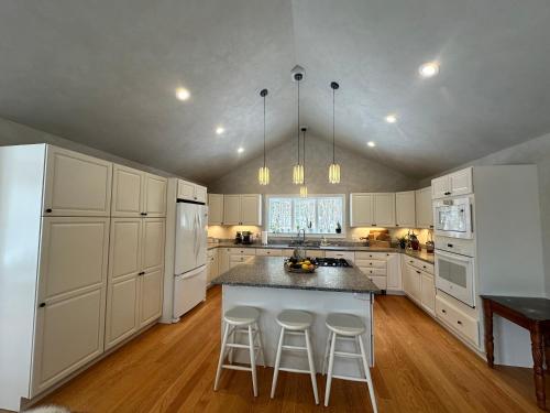 a kitchen with white cabinets and a island with bar stools at Modern House Family Retreat in Bar Harbor