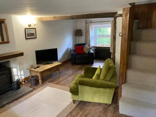a living room with a green chair and a television at Mill Cottage, Upper Hulme in Upper Hulme