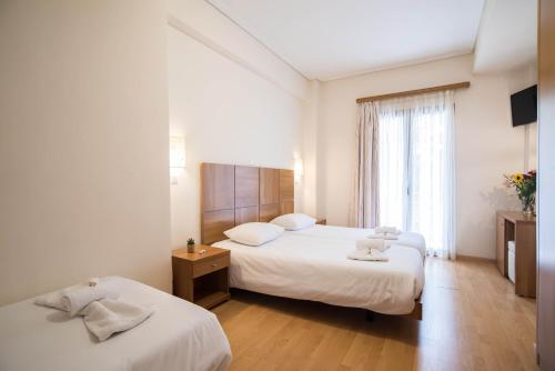 een hotelkamer met 2 bedden en een raam bij THOLOS HOTEL in Delfoi