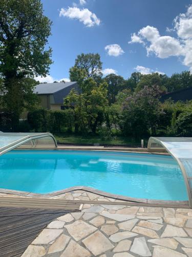 une piscine avec de l'eau bleue dans une cour dans l'établissement GITE Au Dessus des Pâquerettes, à Janville
