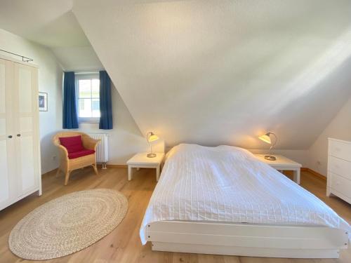 a bedroom with a white bed and a chair at Dünenresidenz Karlshagen - Ferienwohnung Lindenweg 8b in Ostseebad Karlshagen