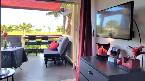 een woonkamer met een bank en een televisie aan de muur bij La Cage Village Naturiste in Cap d'Agde