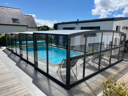 a glass house with a swimming pool on a deck at Maison 10 pers en bord de mer avec piscine chauffée toute l'année, spa et hamman in Surzur