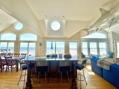 a living room with a table and chairs and windows at Beach Front Luxury Vacation Rental On Lbi in Surf City