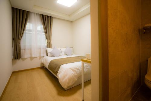 een kleine slaapkamer met een bed en een raam bij Gloryinn in Seoul