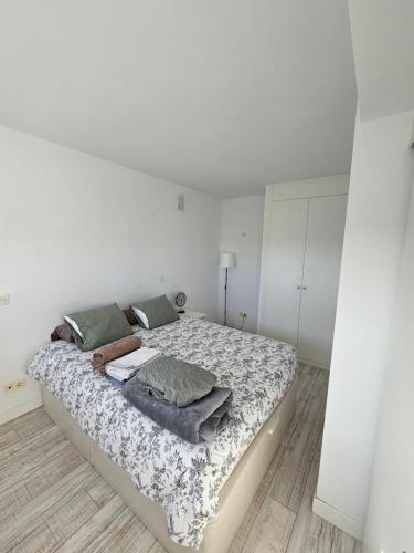 a white bedroom with a large bed with sheets and pillows at Cómodo apartamento en Madrid in Madrid
