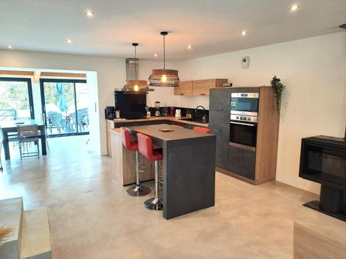 une cuisine avec un îlot doté de tabourets de bar rouge dans l'établissement Maison centre de Saugues avec terrasse et terrain, à Saugues