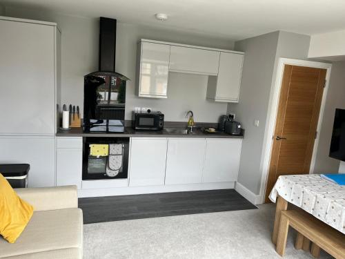 uma cozinha com armários brancos e um micro-ondas em New one bed 1st floor flat close to the beach em Southbourne