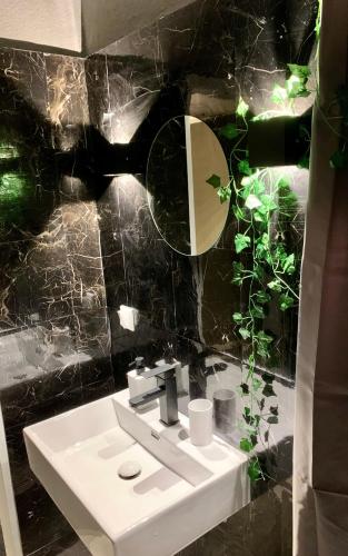 uma casa de banho em azulejos pretos com um lavatório e um espelho. em Leben am Dortmunder U em Dortmund