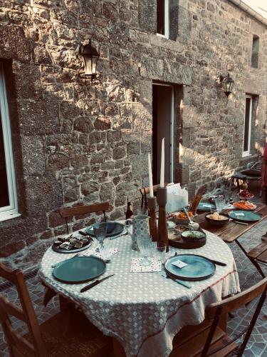 une table avec des assiettes bleues et des bougies sur un mur de briques dans l'établissement Le gîte de barville, à Montfarville