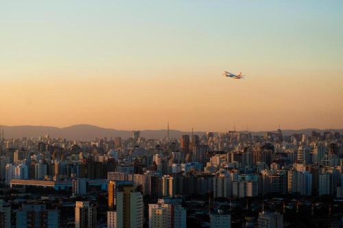 a plane flying over a large city at sunset at Flat Nobile Congonhas in Sao Paulo