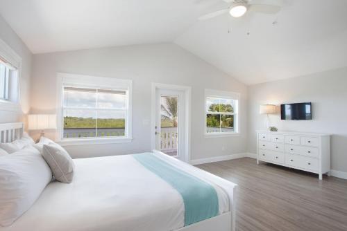 een witte slaapkamer met een bed en 2 ramen bij Isla Key Kiwi - Waterfront Boutique Resort, Island Paradise, Prime Location in Islamorada