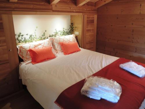 um quarto com uma cama com lençóis brancos e almofadas laranja em Chalet Les Gets, 4 pièces, 6 personnes - FR-1-598-10 em Les Gets