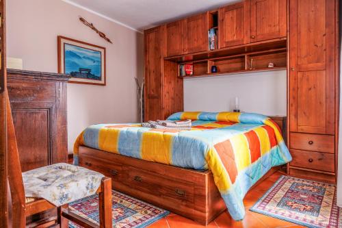 埃多洛Appartamento Panoramico Edolo的一间卧室配有一张床、一把椅子和木制橱柜