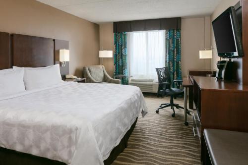 a hotel room with a bed and a desk and a television at Holiday Inn Hotel & Suites Overland Park-West by IHG in Overland Park