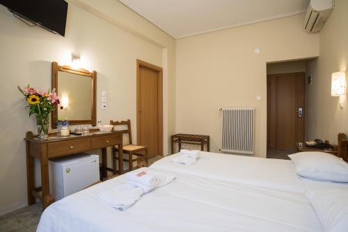 a bedroom with two beds and a desk and a mirror at THOLOS HOTEL in Delfoi