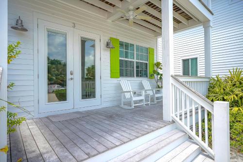 a white house with a porch with two white chairs at Isla Key Lime - Waterfront Boutique Resort, Htd Pool, Dock, Walkable in Islamorada