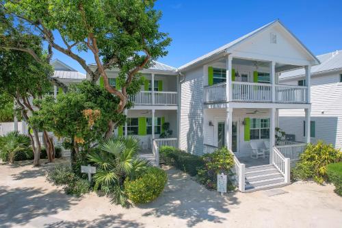 a large white house with a balcony and trees at Isla Key Lime - Waterfront Boutique Resort, Htd Pool, Dock, Walkable in Islamorada