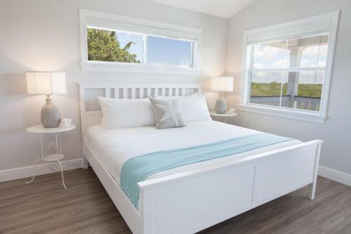 a white bedroom with a white bed and two windows at Isla Key Lychee - Waterfront Boutique Resort, Island Paradise, Prime Location in Islamorada